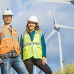 Portrait of two engineers posing in front of wind energy turbine farm